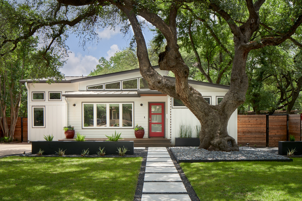 This is an example of a midcentury one-storey white house exterior in Austin with mixed siding, a metal roof, a grey roof and board and batten siding.