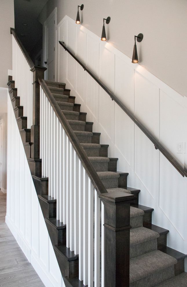 This is an example of a mid-sized arts and crafts carpeted straight staircase in Salt Lake City with carpet risers and wood railing.