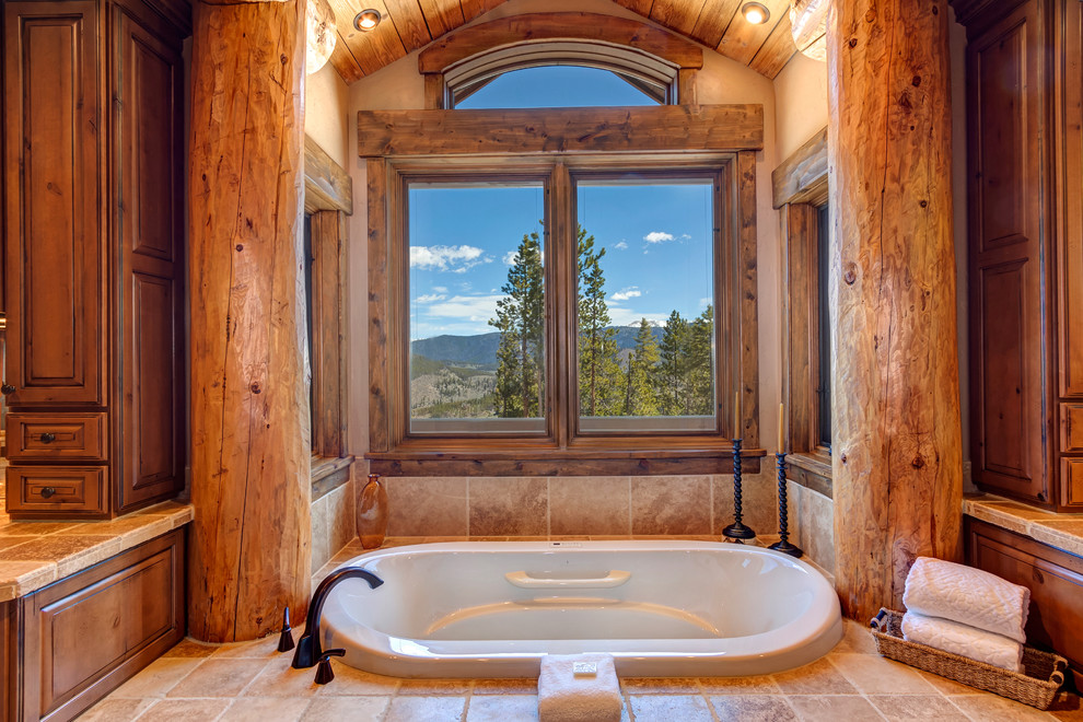 Drop-in bathtub - large rustic master beige tile and limestone tile limestone floor and multicolored floor drop-in bathtub idea with louvered cabinets, dark wood cabinets, beige walls, an undermount sink and a hinged shower door