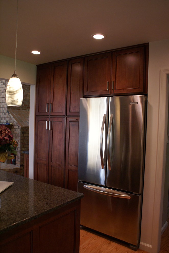 Example of a mid-sized transitional u-shaped light wood floor open concept kitchen design in St Louis with an undermount sink, flat-panel cabinets, dark wood cabinets, quartz countertops, gray backsplash, stone tile backsplash, stainless steel appliances and an island
