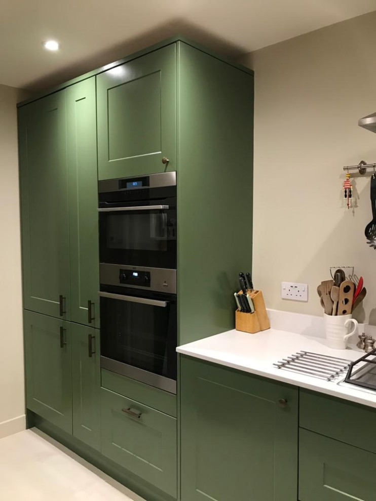 Design ideas for a mid-sized modern kitchen in London with green cabinets, white splashback, white floor and white benchtop.