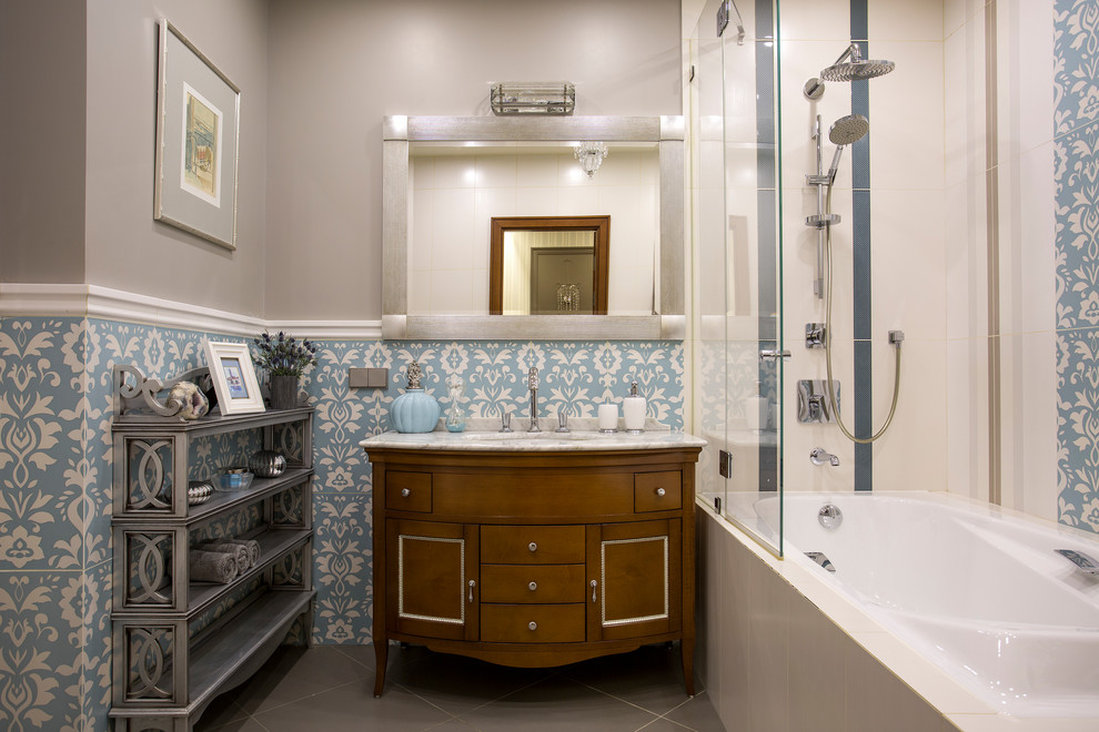 Mid-sized transitional master bathroom in Moscow with medium wood cabinets, an alcove tub, a shower/bathtub combo, blue tile, grey walls, an undermount sink, marble benchtops and grey floor.