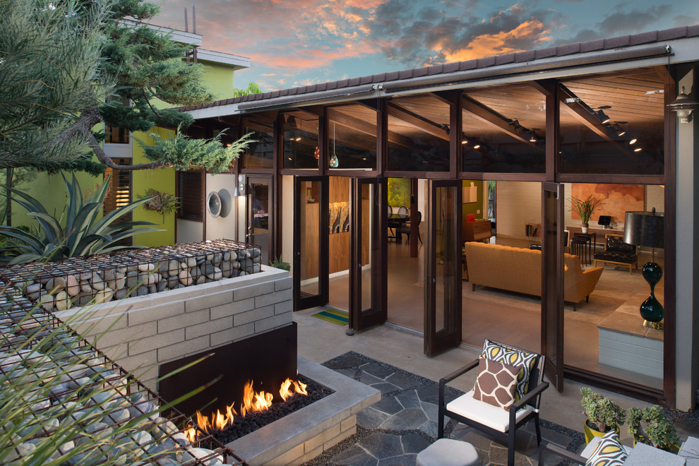 This is an example of a midcentury patio in San Diego with natural stone pavers, no cover and with fireplace.