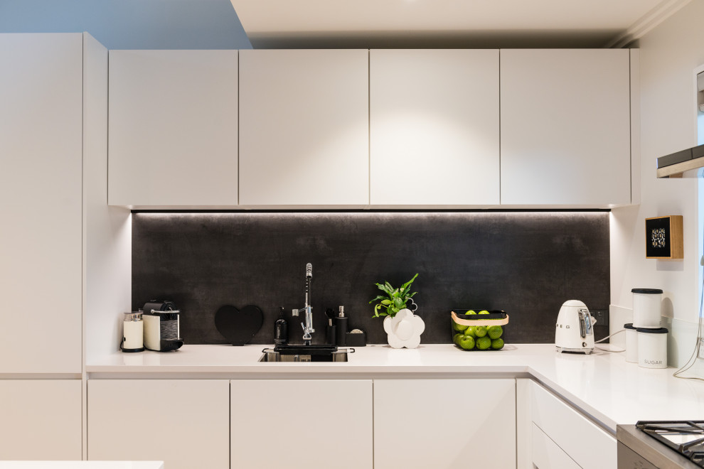 Esempio di una grande cucina minimal con ante lisce, ante bianche, paraspruzzi grigio, elettrodomestici in acciaio inossidabile, pavimento in legno massello medio e top bianco
