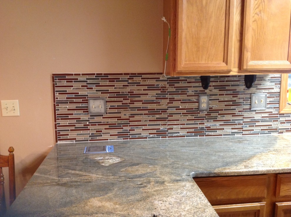Inspiration for a l-shaped eat-in kitchen remodel with an undermount sink, flat-panel cabinets, brown backsplash, glass tile backsplash, stainless steel appliances and a peninsula