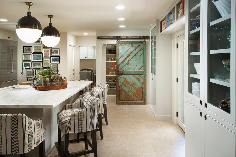 Mid-sized eclectic single-wall eat-in kitchen in Phoenix with an undermount sink, flat-panel cabinets, white cabinets, marble benchtops, white splashback, ceramic splashback, stainless steel appliances, travertine floors and with island.