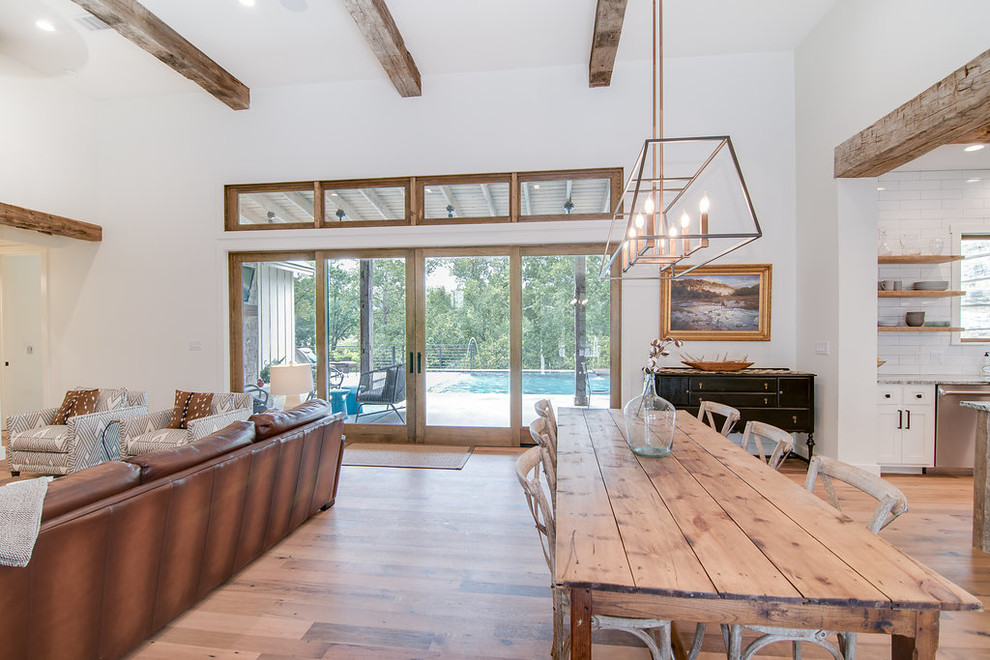 This is an example of a mid-sized country open plan dining in Austin with white walls, light hardwood floors, no fireplace and brown floor.