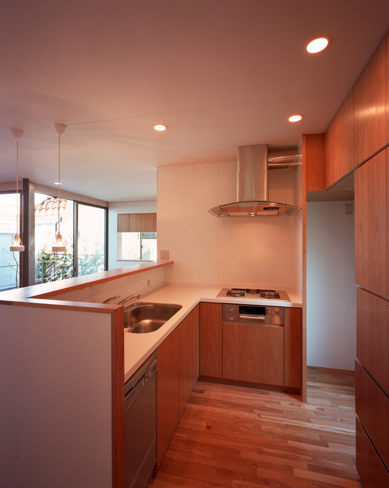 This is an example of a modern l-shaped open plan kitchen in Tokyo with an undermount sink, medium wood cabinets, solid surface benchtops, white splashback, medium hardwood floors, no island, white benchtop and timber.