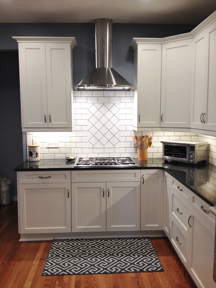 Design ideas for a contemporary eat-in kitchen in Raleigh with a farmhouse sink, shaker cabinets, white cabinets, granite benchtops, white splashback, subway tile splashback, stainless steel appliances and medium hardwood floors.