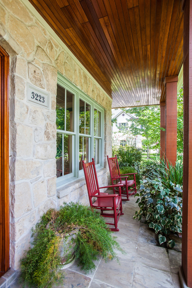 This is an example of a large traditional stone front porch design in Houston with a roof extension.