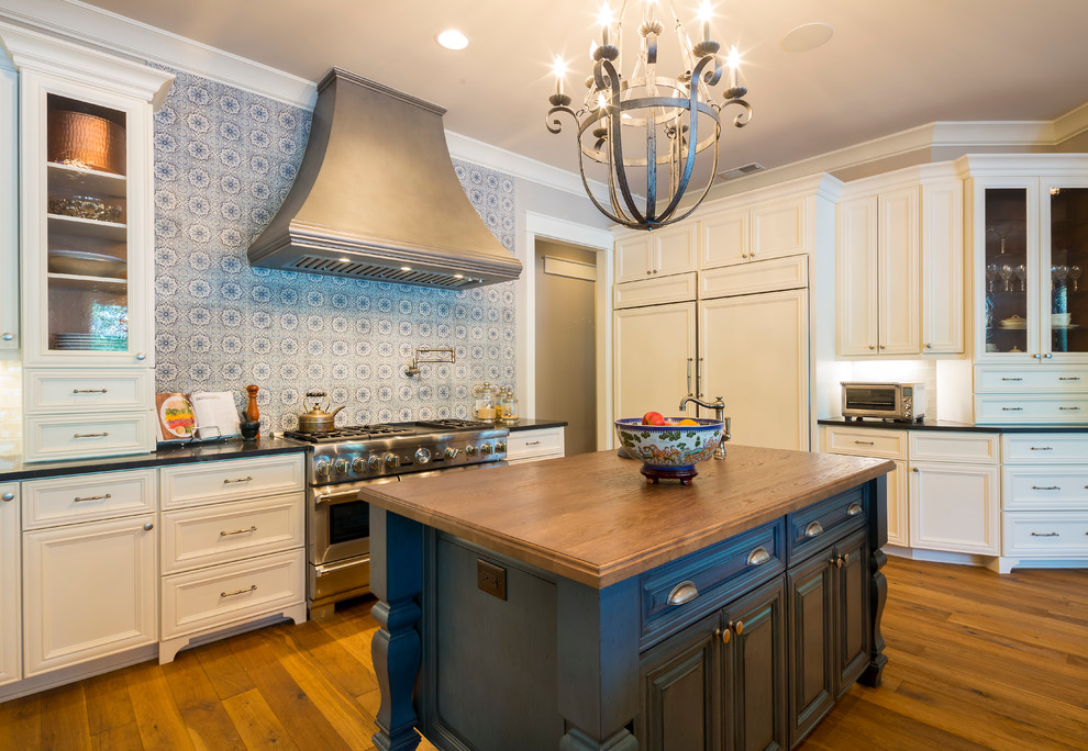Inspiration for an expansive country eat-in kitchen in Charlotte with a farmhouse sink, raised-panel cabinets, white cabinets, granite benchtops, blue splashback, mosaic tile splashback, stainless steel appliances, medium hardwood floors and multiple islands.