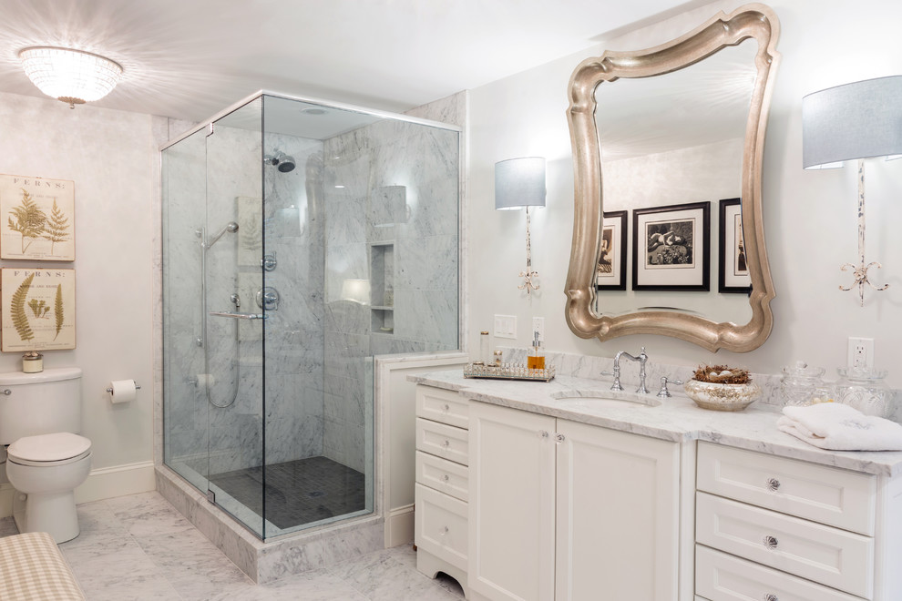 Design ideas for a large contemporary master bathroom in Boston with recessed-panel cabinets, white cabinets, white tile, stone tile, white walls, porcelain floors, an undermount sink, marble benchtops, a corner shower and a two-piece toilet.