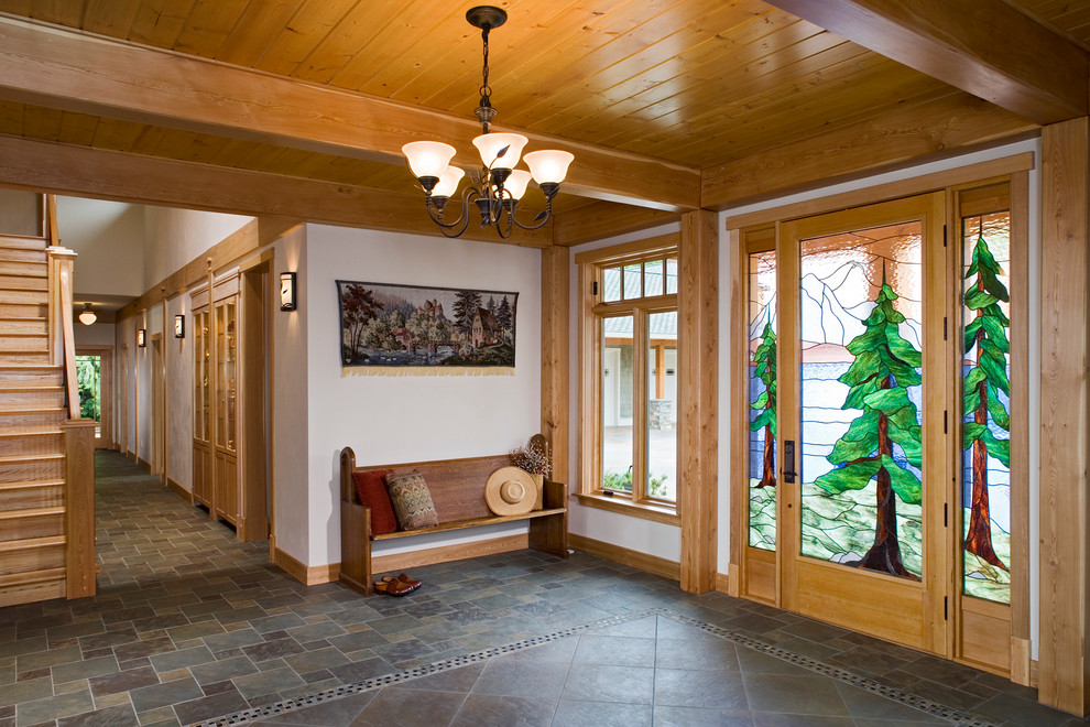 This is an example of a large country foyer in Seattle with white walls, a single front door, a glass front door and slate floors.