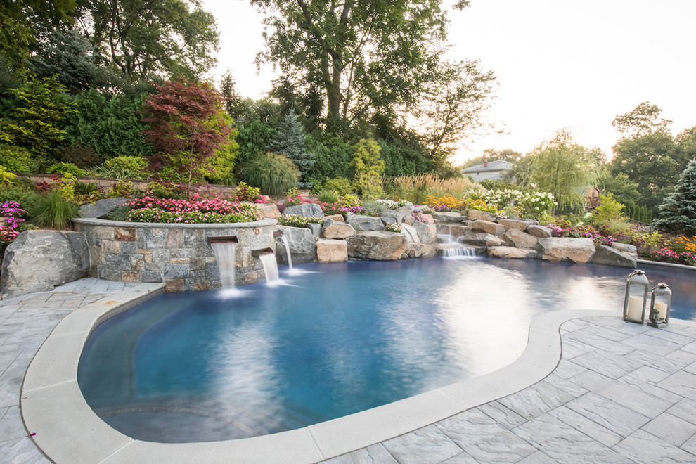 Design ideas for a traditional kidney-shaped natural pool in New York with a water feature and stamped concrete.