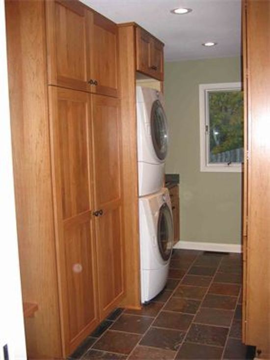 Photo of a laundry room in Minneapolis with medium wood cabinets, terra-cotta floors and a stacked washer and dryer.