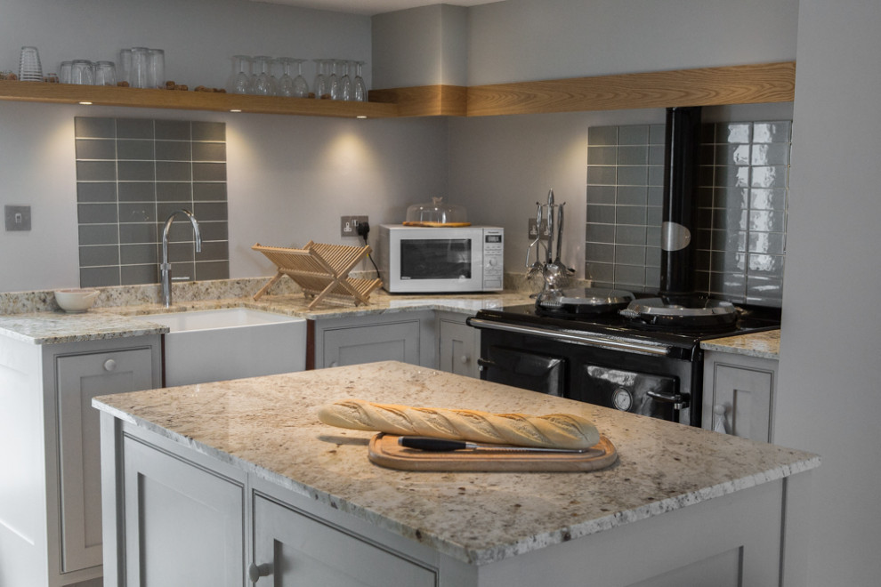 Photo of a rustic grey and white kitchen in Cornwall with a belfast sink, shaker cabinets, grey cabinets, granite worktops, beige splashback, glass tiled splashback, limestone flooring, beige floors and multicoloured worktops.