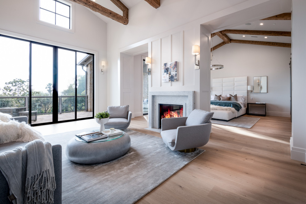 This is an example of a large country master bedroom in Los Angeles with white walls, light hardwood flooring, a two-sided fireplace, a stacked stone fireplace surround, beige floors, exposed beams and panelled walls.