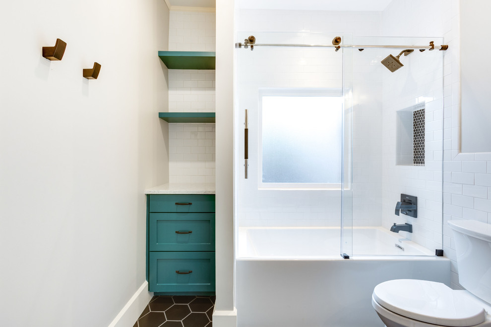 This is an example of a small transitional kids bathroom in Birmingham with recessed-panel cabinets, turquoise cabinets, an alcove tub, a shower/bathtub combo, a two-piece toilet, white tile, subway tile, grey walls, porcelain floors, a console sink, engineered quartz benchtops, black floor, a sliding shower screen and white benchtops.
