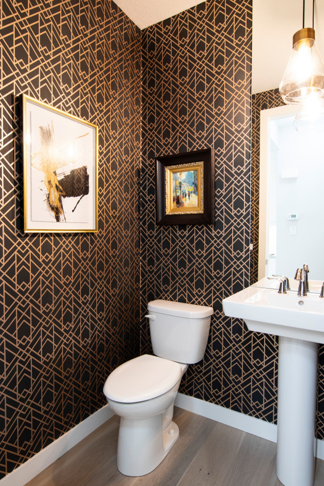 Photo of a small contemporary powder room in Calgary with yellow cabinets, a two-piece toilet, multi-coloured walls, a pedestal sink, a freestanding vanity and wallpaper.