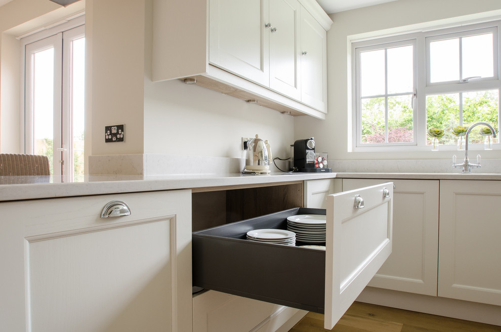 Traditional u-shaped kitchen/diner in Kent with a built-in sink, shaker cabinets, grey cabinets, quartz worktops, black appliances and medium hardwood flooring.