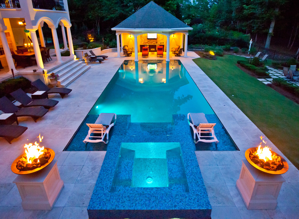 Expansive mediterranean backyard rectangular pool in Other with a hot tub and natural stone pavers.