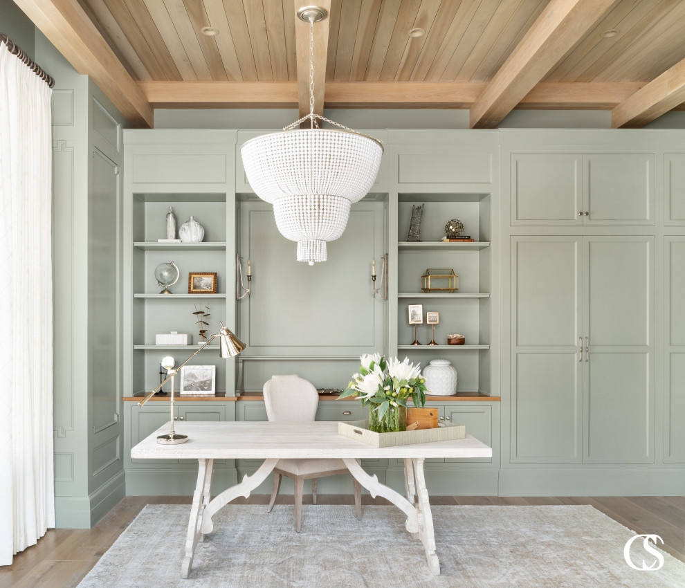 Diseño de despacho tradicional grande con paredes verdes, suelo de madera clara, escritorio independiente y madera
