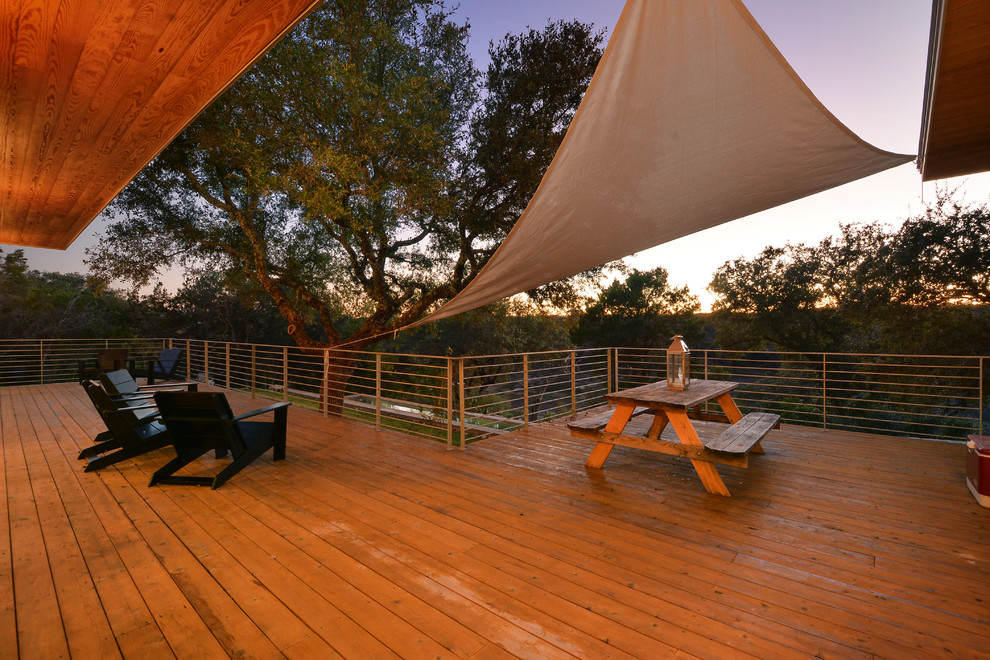 Inspiration for a large industrial backyard deck in Austin with a roof extension.