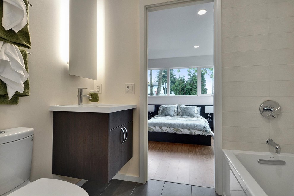 Design ideas for a mid-sized modern 3/4 bathroom in Seattle with flat-panel cabinets, dark wood cabinets, an alcove tub, a two-piece toilet, beige tile, porcelain tile, beige walls, porcelain floors, an integrated sink and engineered quartz benchtops.