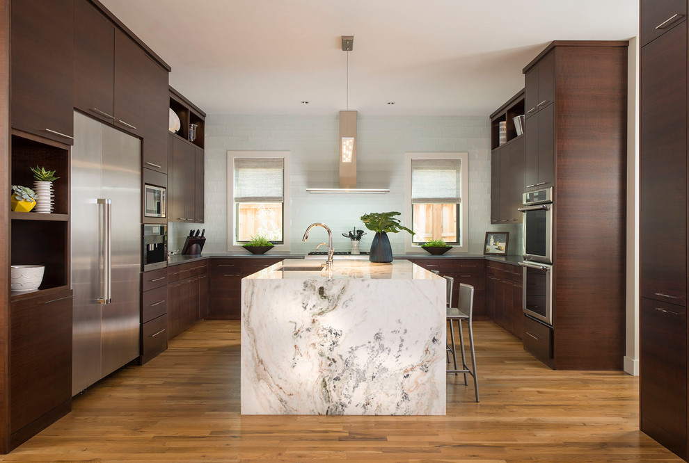 Inspiration for a large contemporary u-shaped separate kitchen in Dallas with an undermount sink, flat-panel cabinets, dark wood cabinets, granite benchtops, white splashback, glass tile splashback, stainless steel appliances, medium hardwood floors and with island.