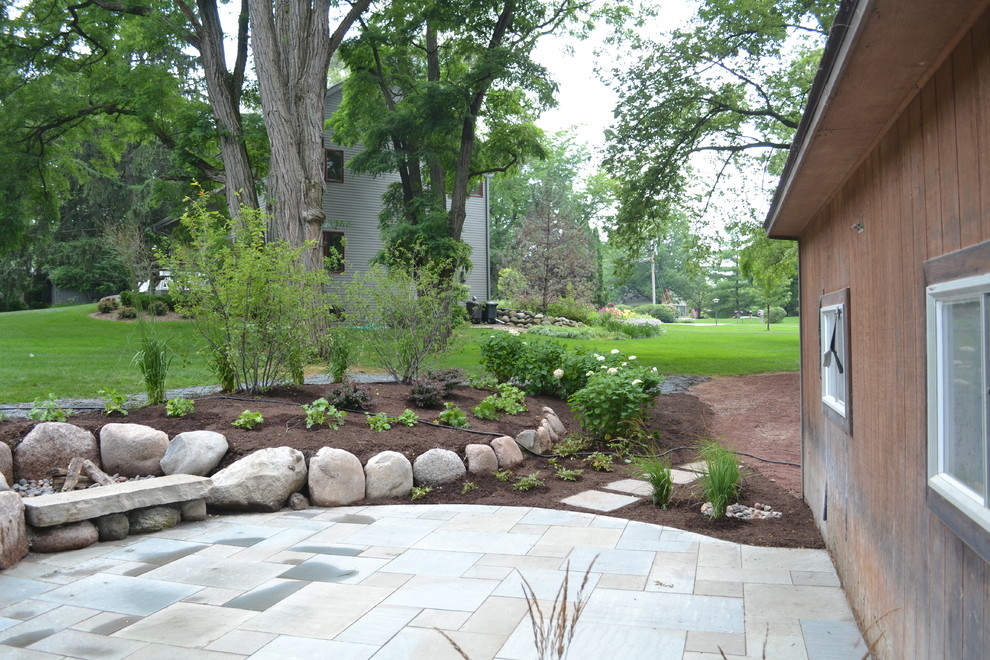 This is an example of a mid-sized rustic backyard stone landscaping in Milwaukee.