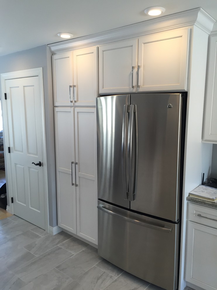 Eat-in kitchen - large transitional l-shaped porcelain tile and gray floor eat-in kitchen idea with an undermount sink, shaker cabinets, white cabinets, granite countertops, stainless steel appliances and no island