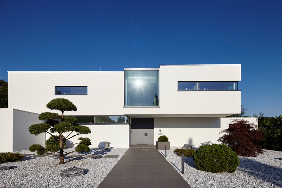 Design ideas for a large modern two-storey stucco white exterior in Dusseldorf with a flat roof.
