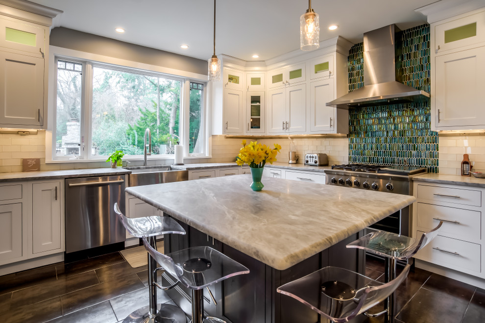 This is an example of a large transitional l-shaped eat-in kitchen in New York with a farmhouse sink, shaker cabinets, white cabinets, quartz benchtops, white splashback, porcelain splashback, stainless steel appliances, porcelain floors, with island, grey floor and multi-coloured benchtop.