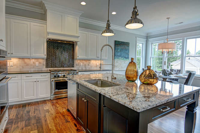Inspiration for a large transitional l-shaped eat-in kitchen in Wilmington with an undermount sink, recessed-panel cabinets, white cabinets, granite benchtops, beige splashback, subway tile splashback, stainless steel appliances, medium hardwood floors, with island and brown floor.