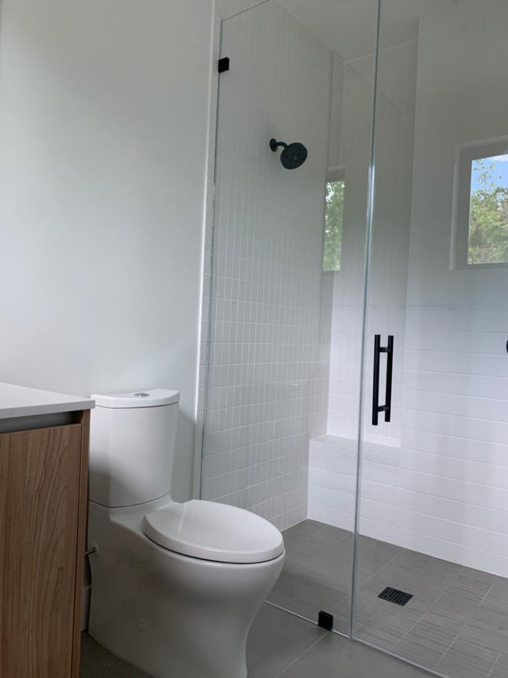Mid-sized modern kids bathroom in Miami with medium wood cabinets, a curbless shower, white walls, grey floor, a hinged shower door, white benchtops, a single vanity and a floating vanity.