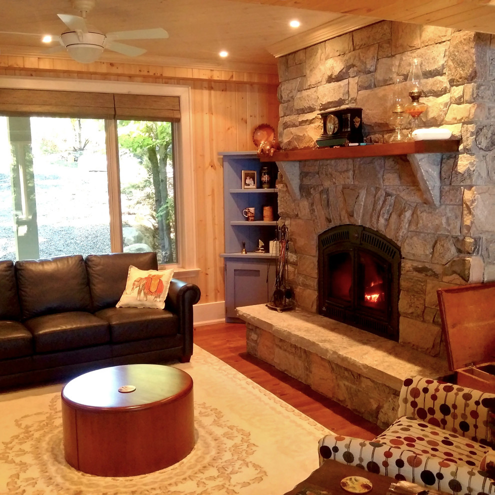 This is an example of a large traditional living room in Toronto with a standard fireplace, a stone fireplace surround, wood and wood walls.