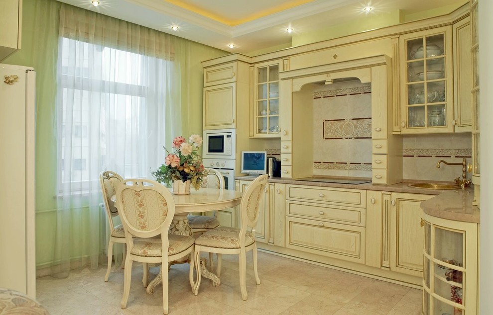 Design ideas for a large traditional l-shaped eat-in kitchen in Moscow with an undermount sink, raised-panel cabinets, beige cabinets, marble benchtops, white splashback, ceramic splashback, white appliances and marble floors.