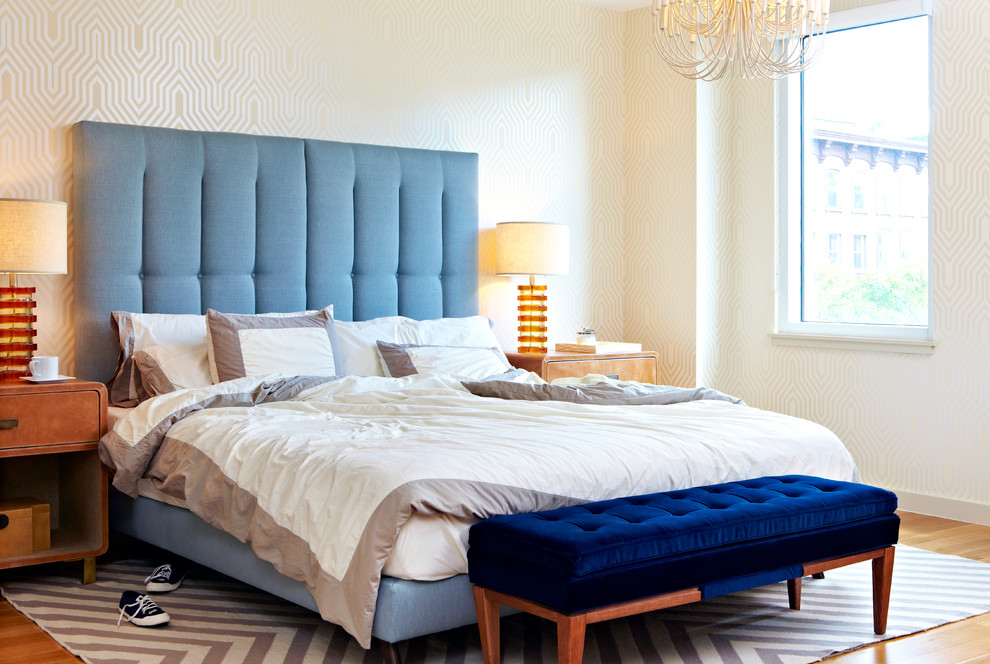 This is an example of a transitional master bedroom in New York with white walls and light hardwood floors.