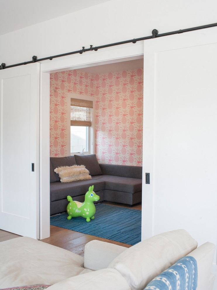 Kids' room - mid-sized contemporary gender-neutral medium tone wood floor and brown floor kids' room idea in Orange County with pink walls