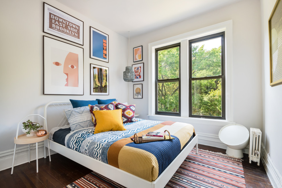This is an example of an eclectic bedroom in New York with white walls, dark hardwood floors and brown floor.