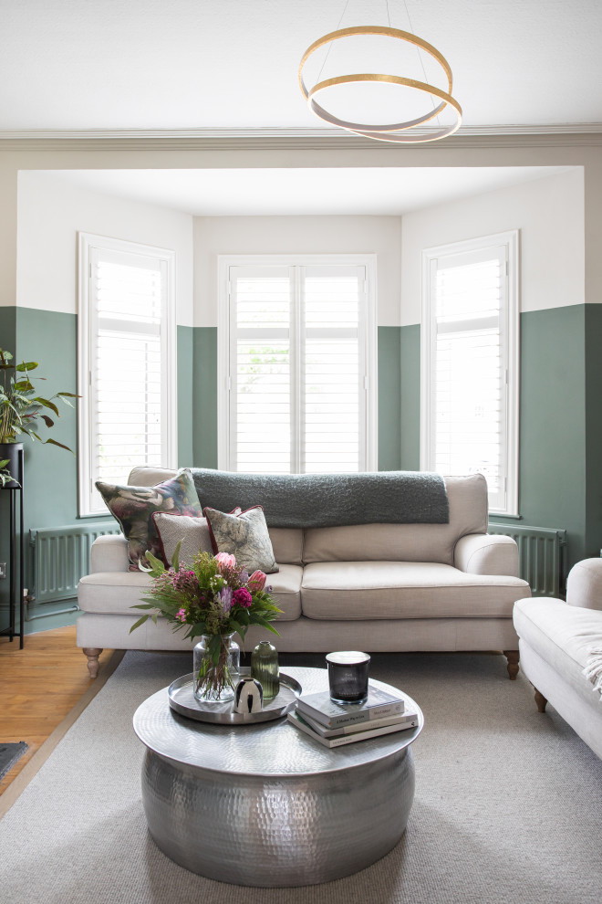 Mittelgroßes Klassisches Wohnzimmer mit grüner Wandfarbe, braunem Holzboden, Kamin, Kaminumrandung aus Holz und Multimediawand in Belfast