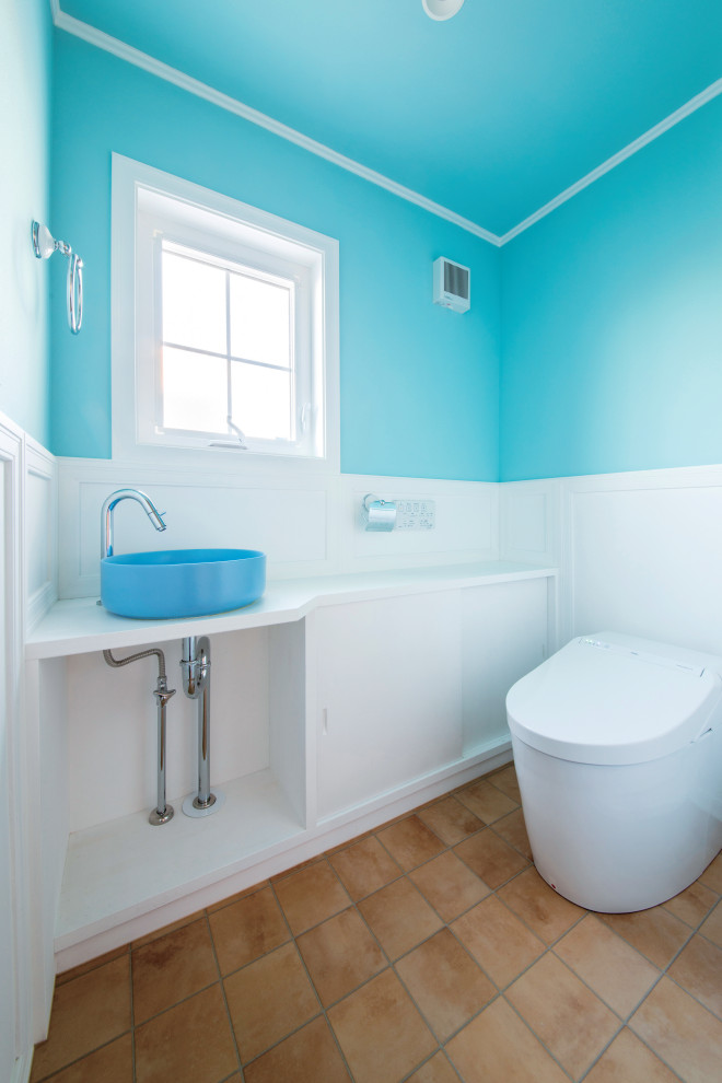 他の地域にある地中海スタイルのおしゃれなトイレ・洗面所 (青い壁、茶色い床、クロスの天井、壁紙) の写真