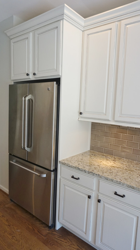 Inspiration for a large transitional u-shaped medium tone wood floor eat-in kitchen remodel in Atlanta with an undermount sink, raised-panel cabinets, white cabinets, granite countertops, gray backsplash, ceramic backsplash, stainless steel appliances and an island