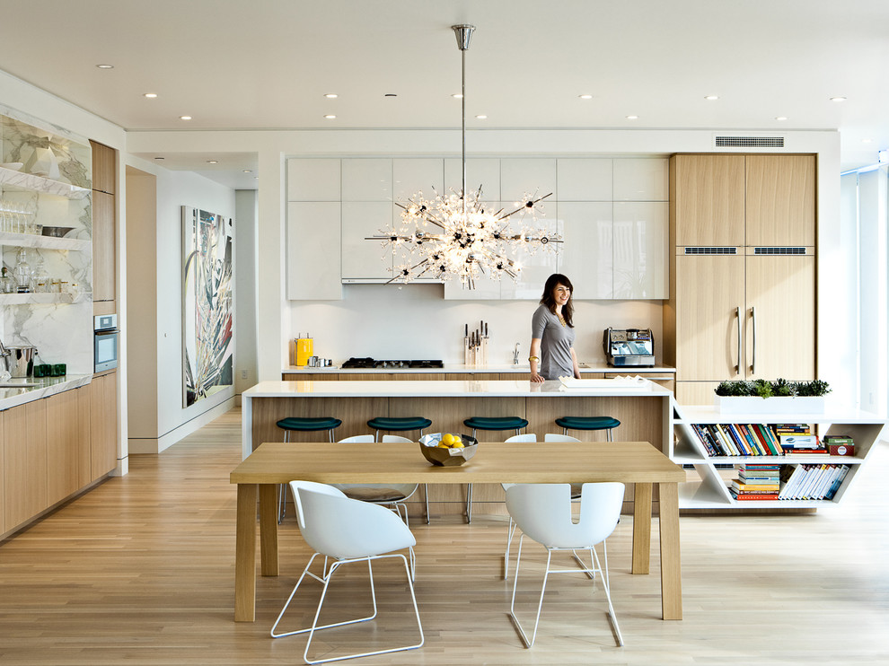 Contemporary eat-in kitchen in Portland with flat-panel cabinets, light wood cabinets, panelled appliances, white splashback and stone slab splashback.