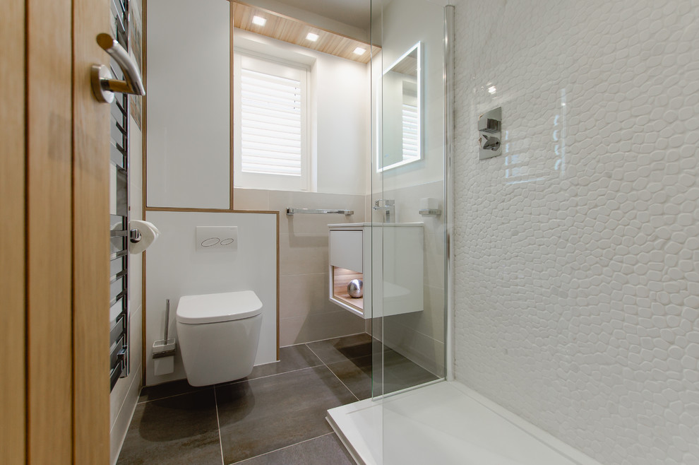 Photo of a small contemporary kids bathroom in Cardiff with open cabinets, white cabinets, an open shower, a wall-mount toilet, white tile, pebble tile, white walls, porcelain floors, an integrated sink, engineered quartz benchtops, brown floor, an open shower, white benchtops, a single vanity and a floating vanity.