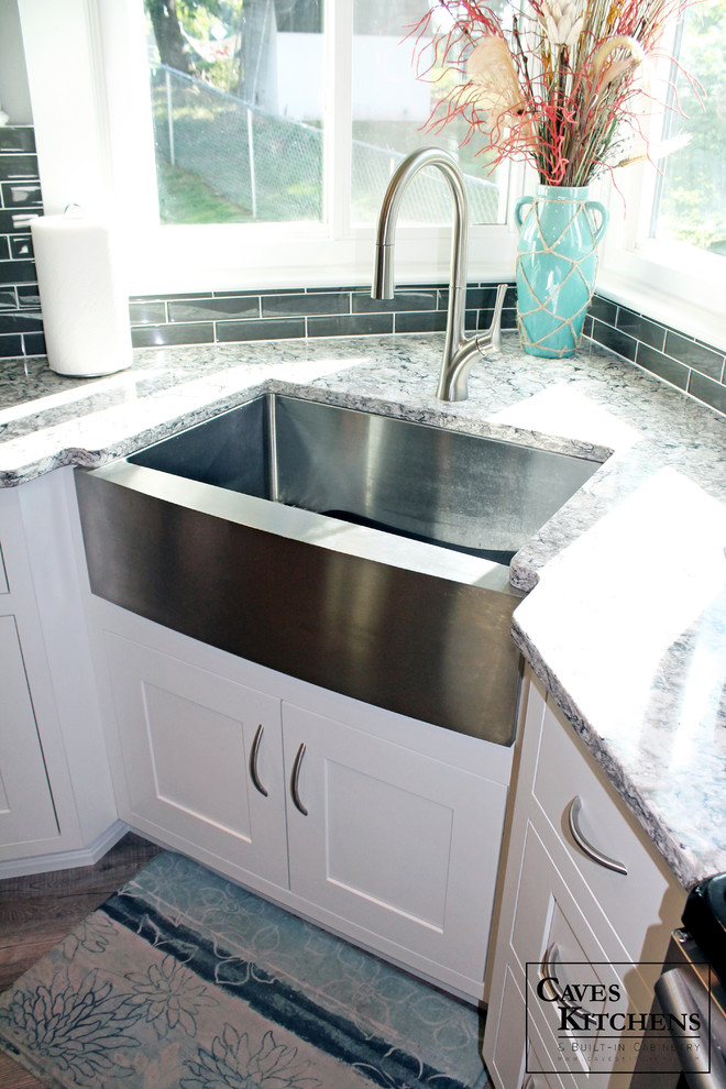 Inspiration for a small transitional l-shaped medium tone wood floor home design remodel in New York with a farmhouse sink, recessed-panel cabinets, white cabinets, quartz countertops, black backsplash, subway tile backsplash, stainless steel appliances and no island
