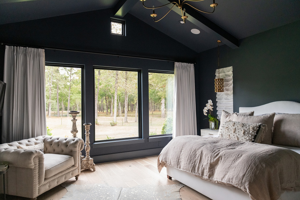 This is an example of a large country master bedroom in Houston with black walls, light hardwood floors, no fireplace, beige floor, vaulted and wood walls.