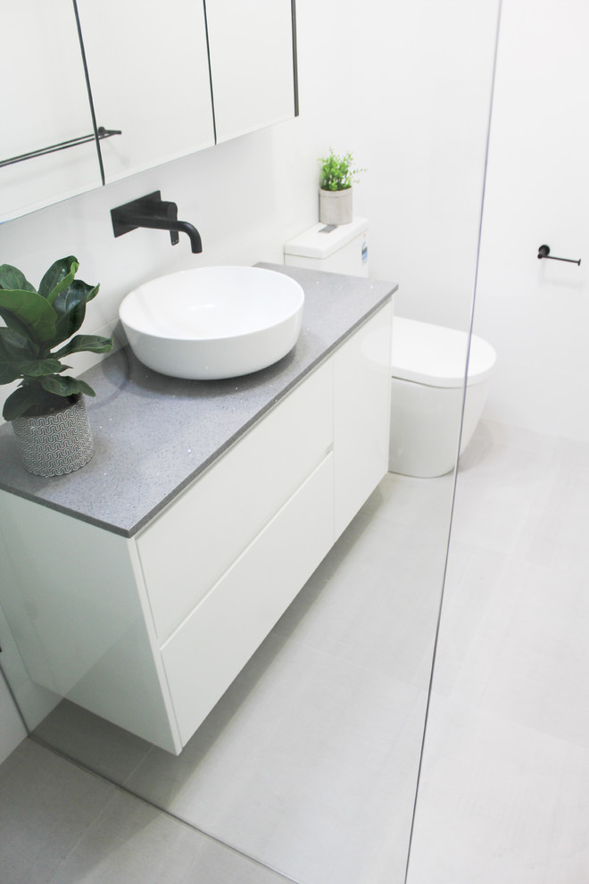 Inspiration for a small modern 3/4 bathroom in Perth with flat-panel cabinets, white cabinets, an open shower, a one-piece toilet, gray tile, porcelain tile, grey walls, porcelain floors, a vessel sink, solid surface benchtops, grey floor, an open shower and grey benchtops.