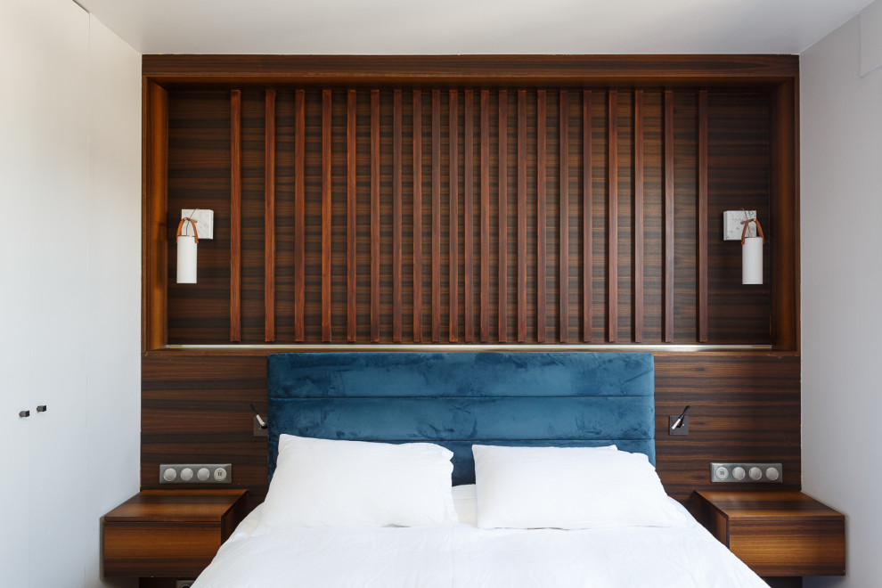 Ejemplo de dormitorio principal y blanco y madera actual de tamaño medio sin chimenea con paredes blancas, suelo de madera clara y suelo marrón