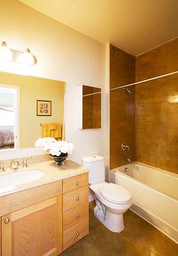 Photo of a mid-sized contemporary master bathroom in San Francisco with a drop-in sink, recessed-panel cabinets, light wood cabinets, an alcove tub, a shower/bathtub combo, a one-piece toilet, beige walls and concrete floors.
